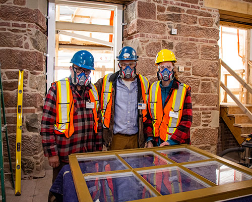 The Heritage Retrofit Carpentry team pose with a completed window pane inside Province House National Historic Site