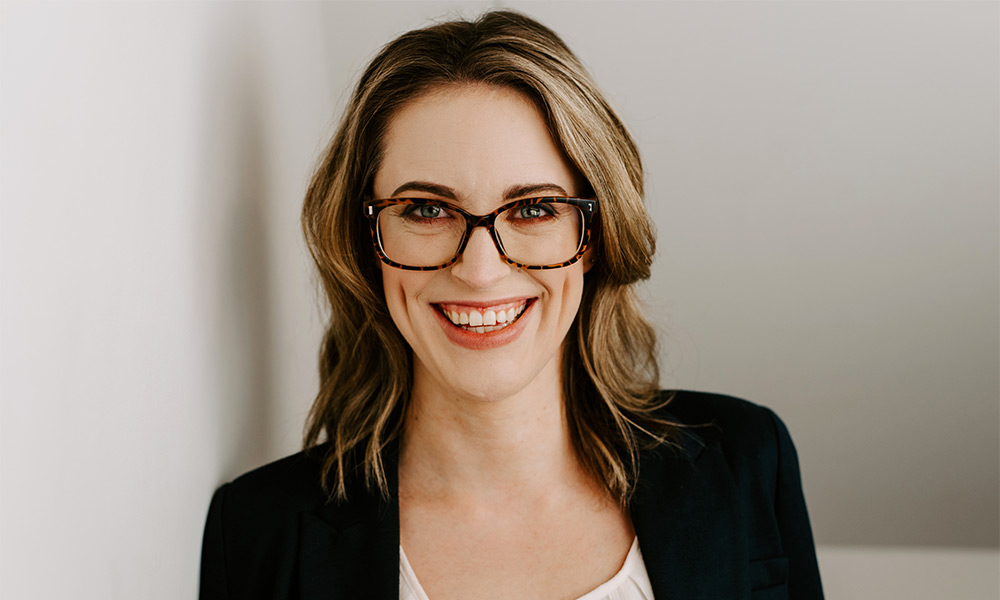 Female with sandy brown hair and glasses smiling